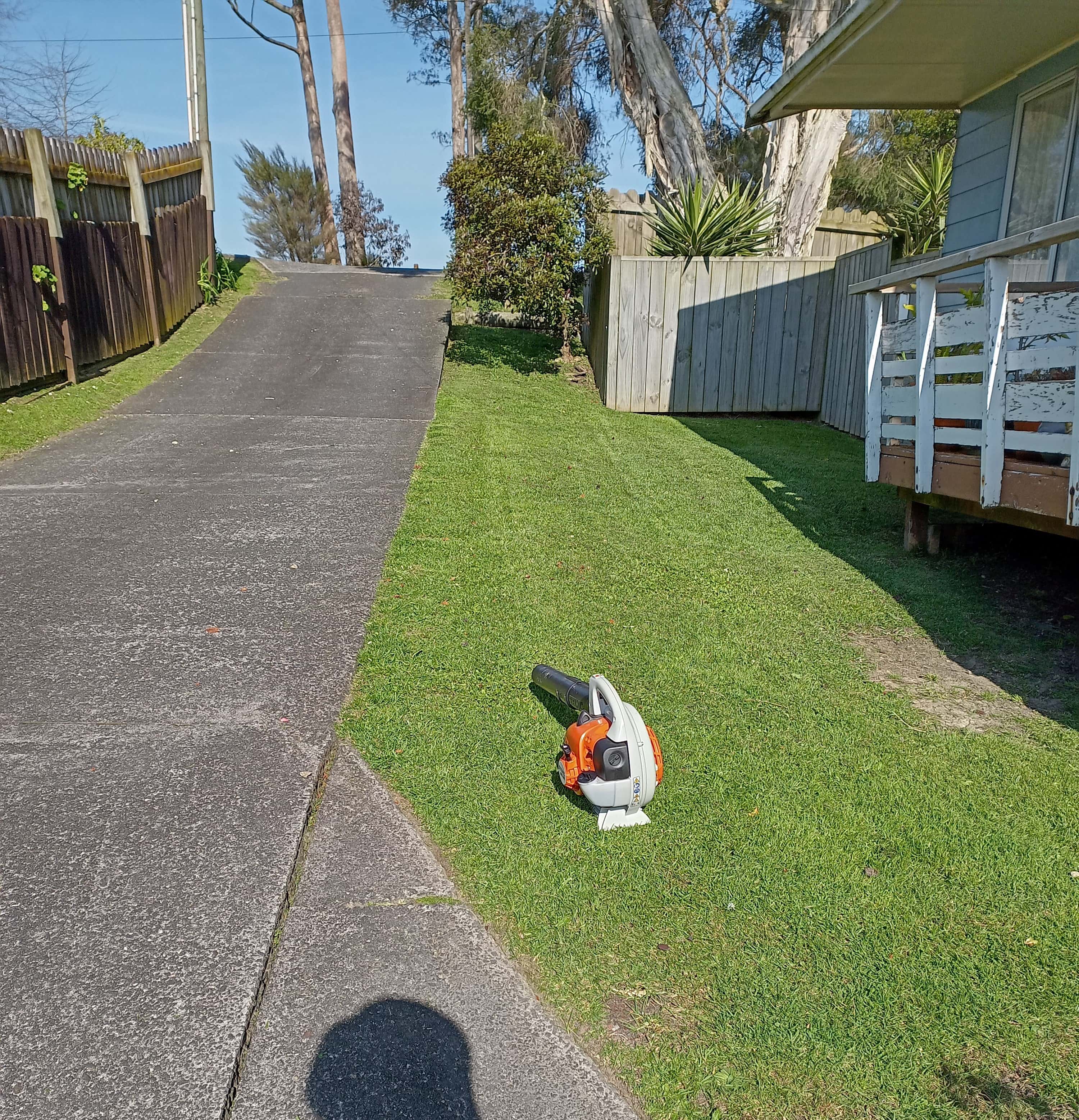 Front lawn freshly mown with the mulch mower, and Stihl leaf blower sitting on the grass.